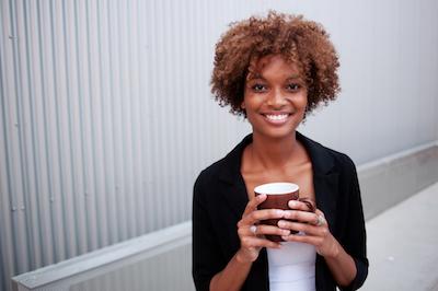 woman smiling while holding cup of coffee