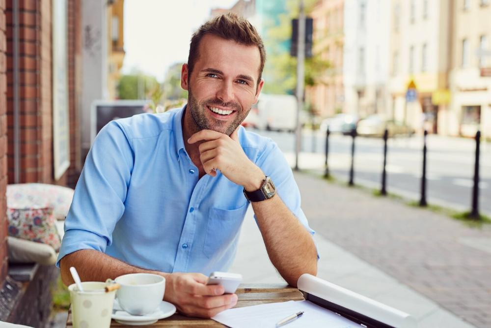 man smiling while sitting at cafe table