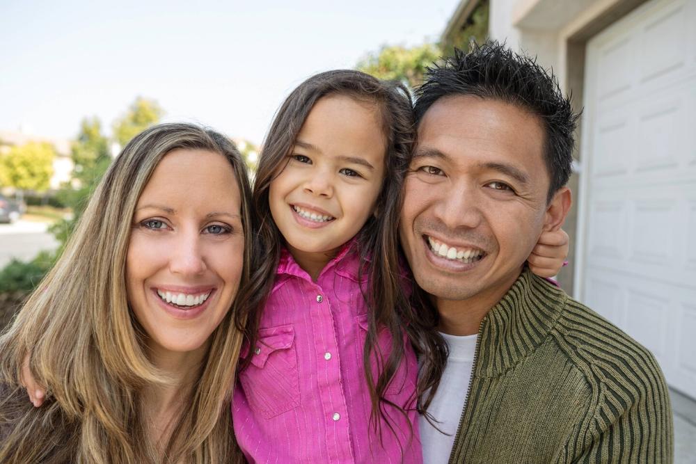 mother, father, and young daughter smiling